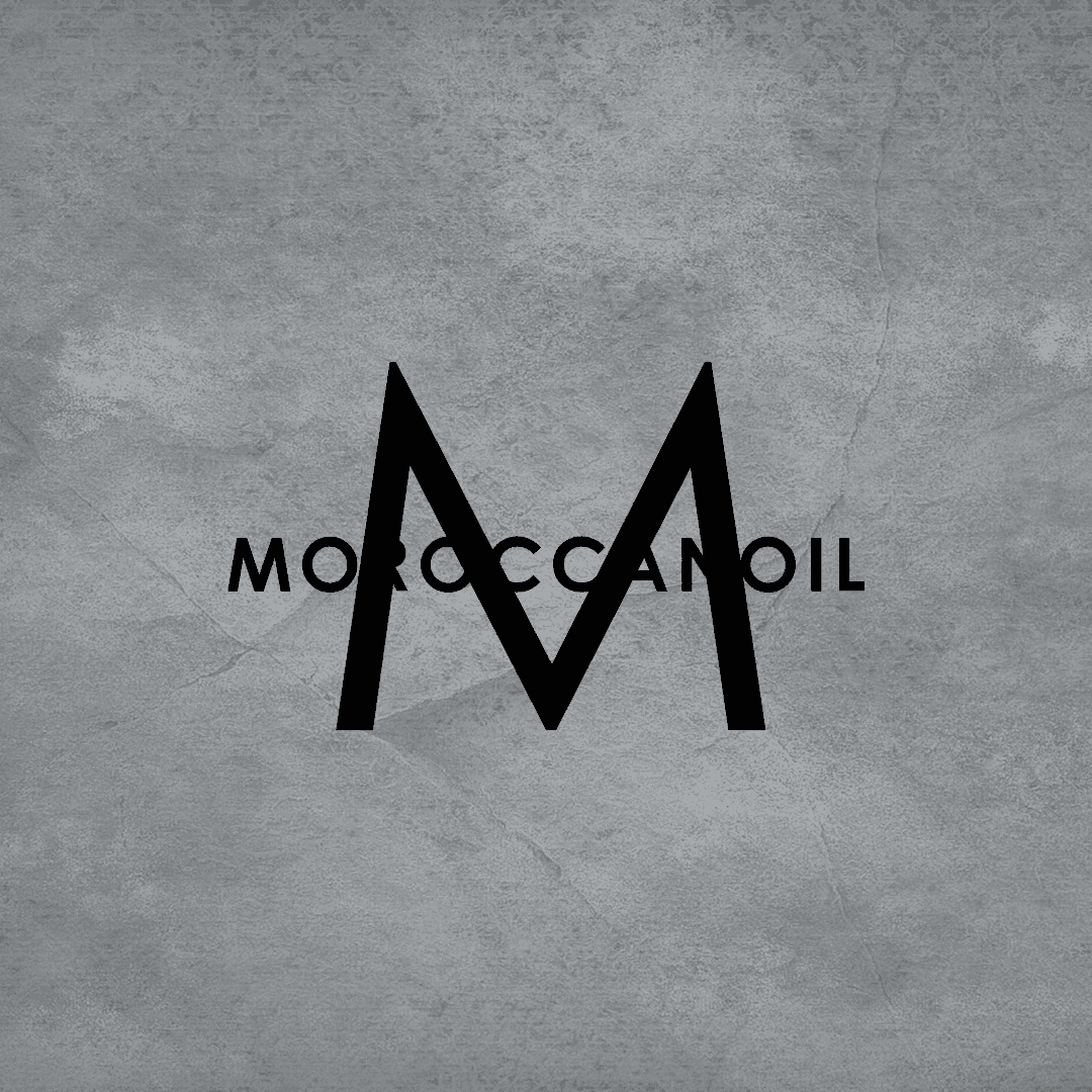 Logo displaying a large black 'M' with the word "Moroccanoil" across it on a textured gray background.