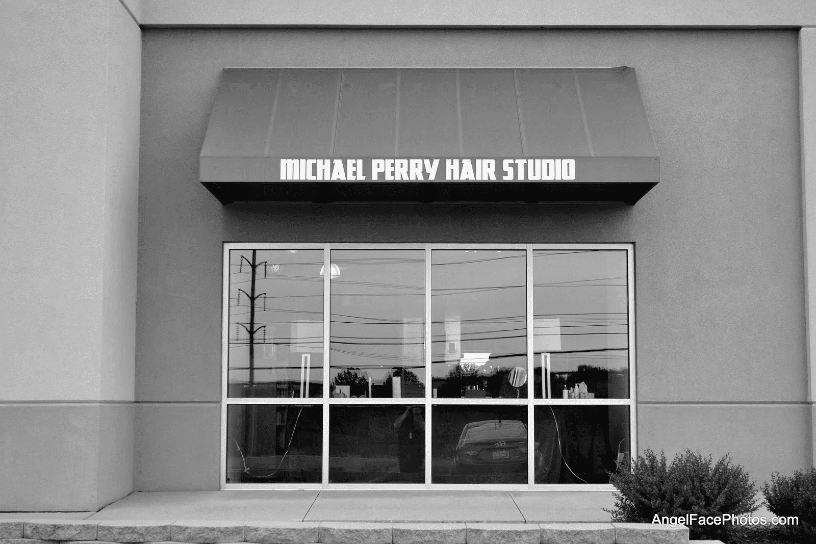 Storefront of a hair studio with a blue awning.