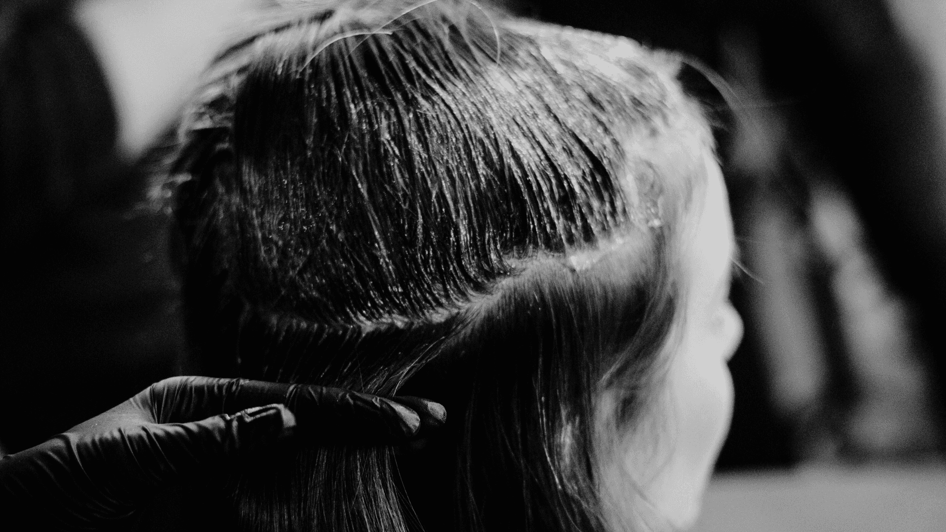 Hair stylist sectioning and coloring a client's hair in a salon.